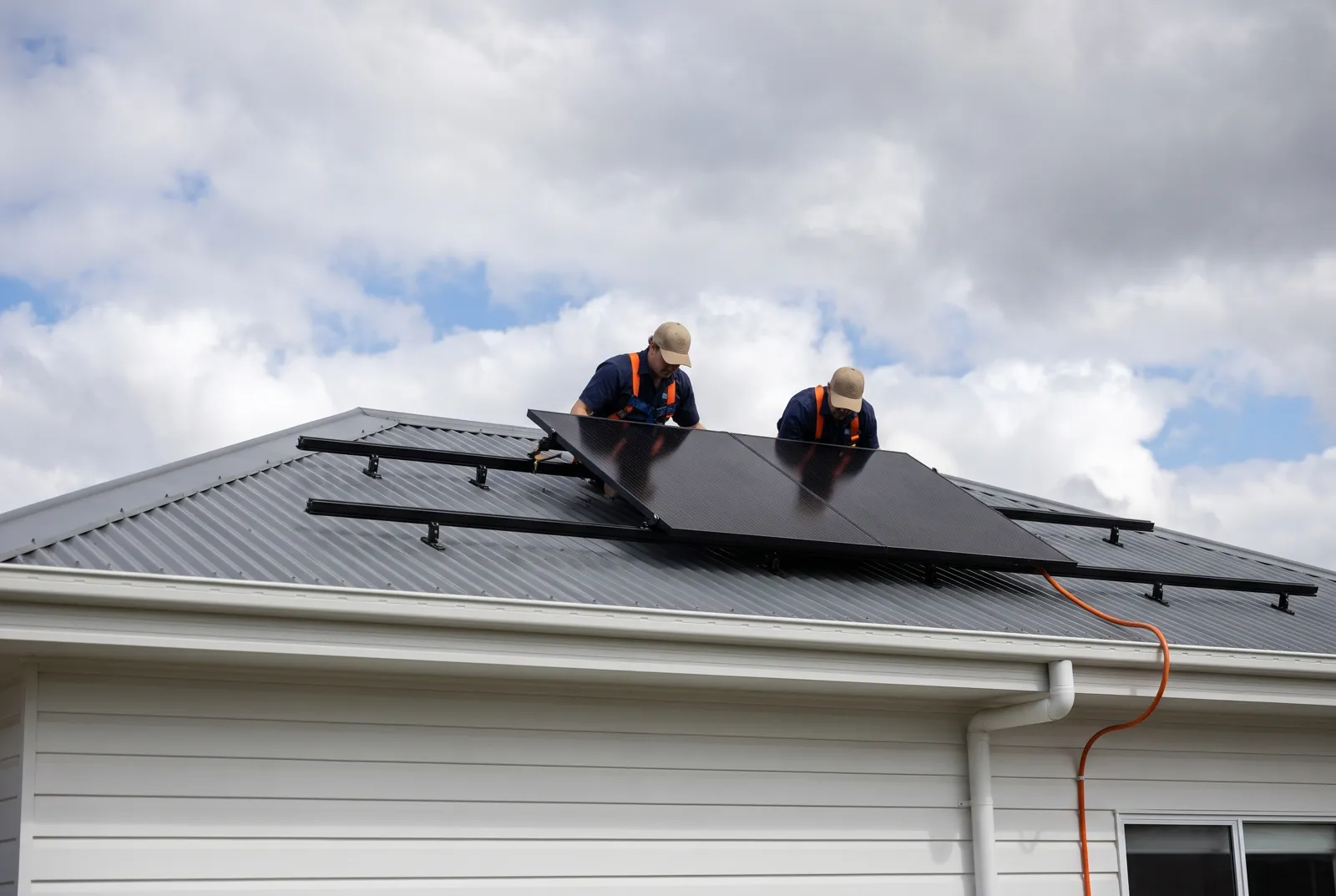 Two installers placing the first panel on a roof